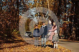 Mother with four kids in autumn park. Family walk in fall forest