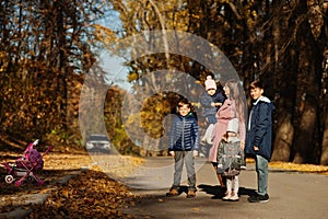 Mother with four kids in autumn park. Family walk in fall forest