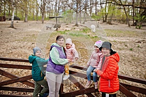 Mother with four kids discovering and watching animals at zoo