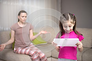 Mother frustrating that her daughter playing video games. photo