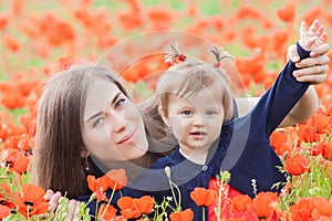 Mother with funny child outdoor at poppy flowers field