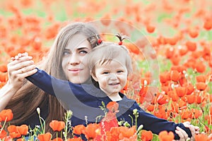 Mother with funny child outdoor at poppy flowers field