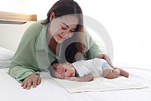 Mother gentle touching newborn infant baby boy on bed in white bedroom, lovely family mom and child stand time together, parent