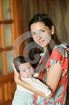 Mother gently hugs the baby. at home. Mom and newborn baby. Mom hugs and holds the newborn baby in her arms, the newborn sleeps in