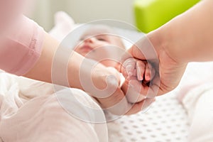 Mother gently massaging her baby boy while applying body lotion to his skin. Baby massage background. Hands close up. photo