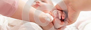 Mother gently massaging her baby boy while applying body lotion to his skin. Baby massage banner. Hands close up.