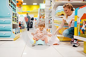 Mother with girl choosing baby potty in kids store