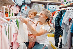 Mother with girl choosing clothes in kids store