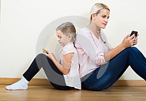 Mother and girl playing with mobile phones indoor