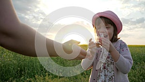 Mother gives child daughter drink clean pure water on sunset nature, cute female girl drinking water from glass, little