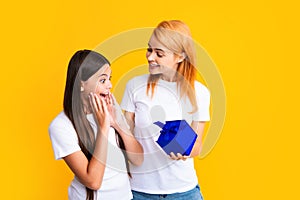 Mother gives a gift to her teen daughter, isolated background. Happy family concept. Girl with mother together