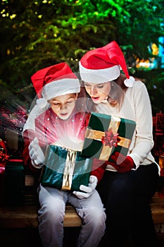 Mother gives her child a Christmas gift box with light rays and