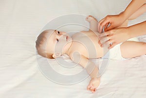 mother gives massage to baby lying on the bed on white background