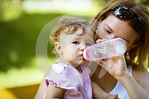 Mother gives to her child to drink water from a bottle