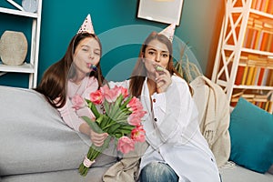 Mother giving birthday cake to funny little girl at home