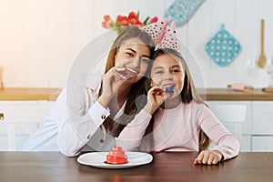 Mother giving birthday cake to funny little girl at home