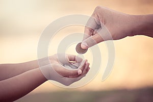 Mother giving coin to child as saving money concept