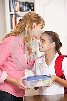 Mother Giving Daughter Healthy Lunchbox In Kitchen