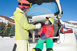 Mother giving her son cup of tea after skiing