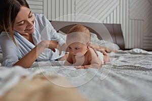 Mother giving opportunity for baby to crowl on bed