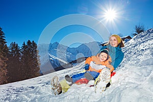 Mother go downhill together with little boy siting in the sledge