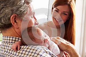 Mother And Grandfather With Sleeping Newborn Baby Daughter