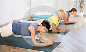 Mother, grandmother and adolescence son do exercise elbow plank pose Sampatasana.