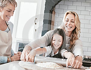 .Mother, grandmother and child cooking and baking with rolling pin for pastry, pie or pizza together in family kitchen