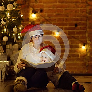 Mother or grandmother with her little son or grandson reading a magic book in cozy living room