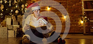 Mother or grandmother with her little son or grandson reading a magic book in cozy living room