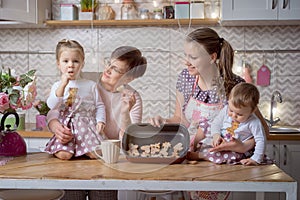 Mother and grandmother with two daughters with cookies in the kitchen