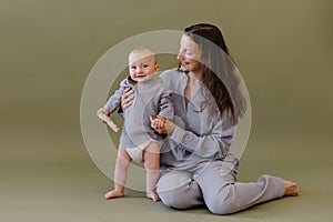 Mother in grey clothes pajamas hug a baby.  Mom and child. Happiness of motherhood. Eco parenting vegan.