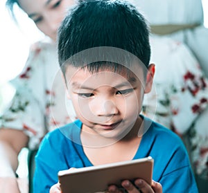 Mother guiding her son to use tablet the right way