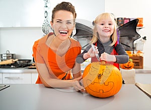 Mother with halloween dressed daughter creating Jack-O-Lantern