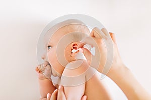 Mother hand cleaning baby ear with cotton swab