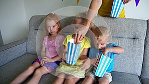 Mother hand give popcorn boxes for children watching tv television