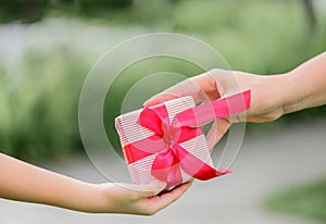 Mother hand giving a gift box to her child. Holidays, present,