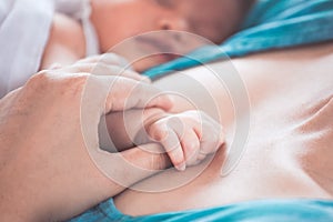 Mother hand holding asian newborn baby girl hand while she sleep