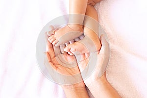 Mother hands holding baby feet lying on a comfortable bed at home,Family concept