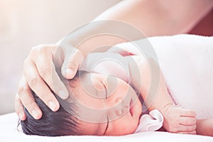 Mother hand touching asian newborn baby girl head
