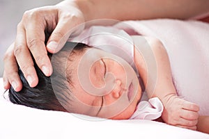 Mother hand touching asian newborn baby girl head