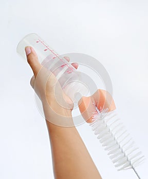 Mother hand washing baby milk bottle by bottle brush on white background