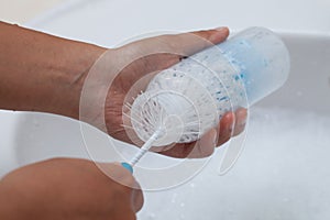 Mother hand washing baby milk bottle