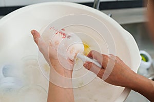 mother hand washing baby plastic milk bottle