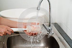 mother hand washing baby plastic milk bottle