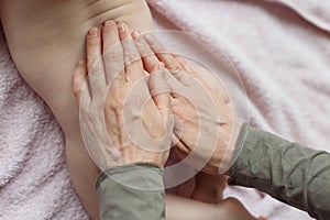 Mother hands applying cream on baby after bathing in room. hands of a mother massaging her baby`s feet, in bed at home