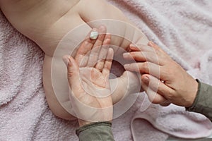 Mother hands applying cream on baby after bathing in room. hands of a mother massaging her baby`s feet, in bed at home