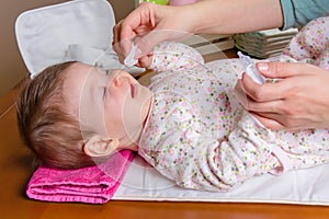 Mother hands cleaning eyes of baby with cotton