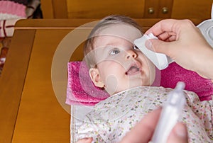 Mother hands cleaning eyes of baby with cotton