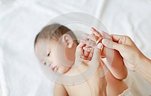 Mother hands massaging finger of baby on the bed at home